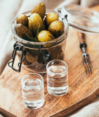 Pickled cucumbers in a small jar and two vodka  shotsの写真素材