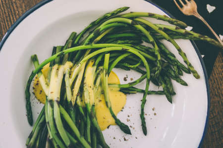 Boiled green asparagus dressed in mustard vinegar and olive oil dressing mayonnaise or hollandaise sauce. Toned pictureの写真素材
