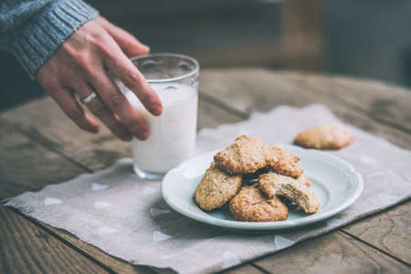 Homemade oat and nut cookies and glass of milk on wooden table. Toned pictureの写真素材