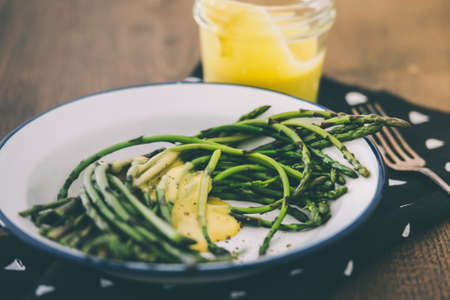 Boiled green asparagus dressed in mustard vinegar and olive oil dressing mayonnaise or hollandaise sauce. Toned pictureの写真素材