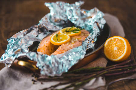 Salmon steak baked with lemon and herbs in foilの写真素材