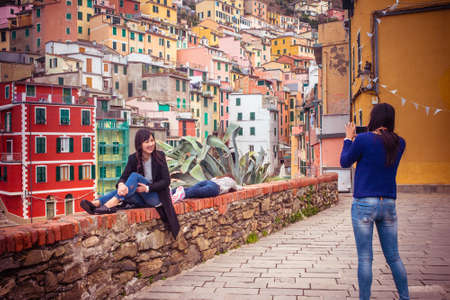 RIOMAGGIORE IN CINQUE TERRE, ITALY - MARCH 10, 2015: Tourists taking photo in Riomaggiore, one of...