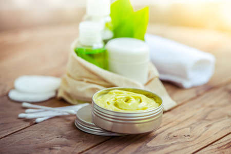 Cosmetic bottle container with green herbal leaves in small organic cotton bag on wooden backgroundの写真素材