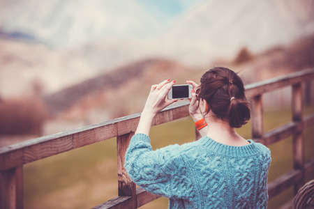 Girl making pictures on terrace with beautiful mountain view. Toned imageの写真素材
