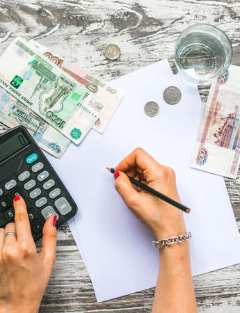 Woman counting russian rouble money with calculator. Business concept. Top viewの写真素材