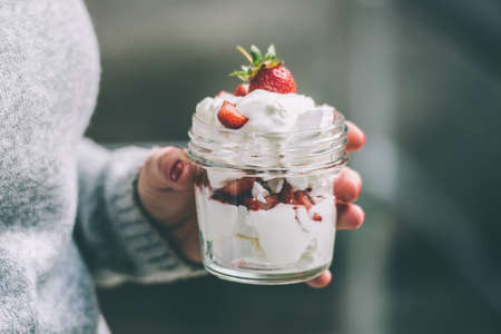 Classic british summer dessert called Eton Mess. Strawberries, crushed meringue and whipped cream in jar. Toned imageの写真素材