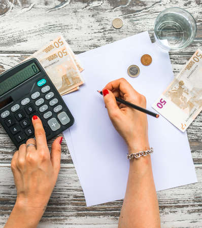 Woman counting euro money with calculator. Business concept. Top viewの写真素材