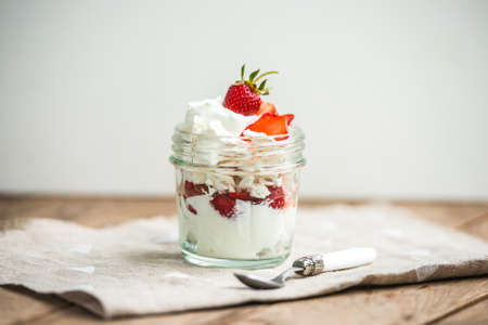 Classic british summer dessert called Eton Mess. Strawberries, crushed meringue and whipped cream in jarの写真素材