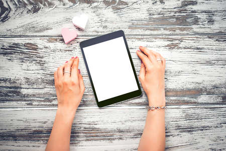 Female hands holding electronic tablet with copy space old wooden table. Top viewの写真素材