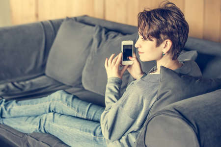 Young beautiful woman sitting with smart phone. Toned imageの写真素材
