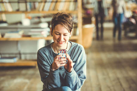 Young beautiful woman sitting with smart phoneの写真素材