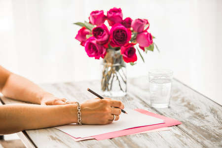 Woman writing on  blank paper sheets on old wooden tableの写真素材