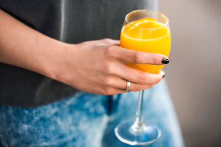 Close-up of female hand holding glass with cocktail with orange. Selective focus and shallow DOFの写真素材