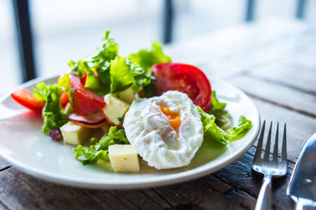 Fresh vegetable salad with poached egg on wooden backgroundの写真素材
