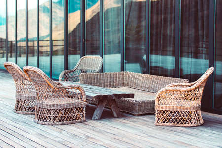 Rattan chairs and wooden table on terrace in mountainsの写真素材