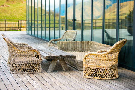 Rattan chairs and wooden table on terrace in mountainsの写真素材