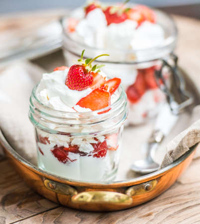 Classic british summer dessert called Eton Mess. Strawberries, crushed meringue and whipped cream in jarの写真素材