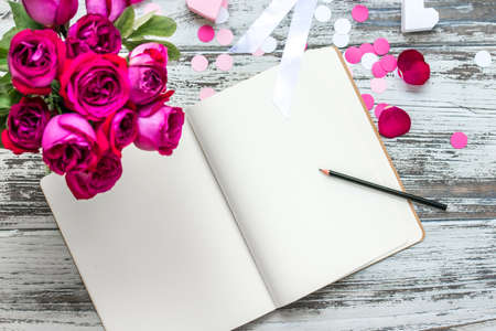 Bouquet of roses and open notebook on old wooden table. Top viewの写真素材
