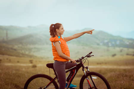 Beautiful girl riding on bicycle outdoor on the rural roadの写真素材