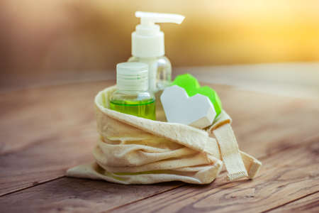 Cosmetic bottle containers in small organic cotton bag on wooden backgroundの写真素材