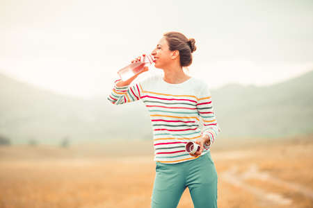 Beautiful girl drinking water outdoorの写真素材
