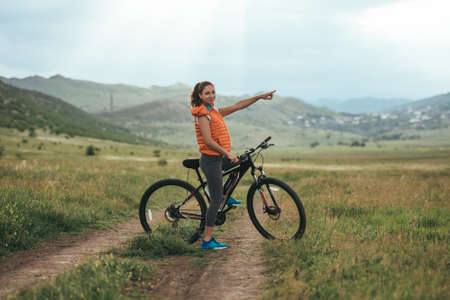 Beautiful girl riding on bicycle outdoor on the rural road.の写真素材