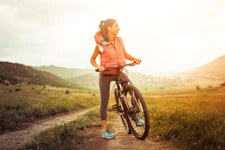 Beautiful girl on riding bicycle outdoor on the rural roadの写真素材