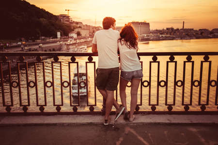 Silhouette of bridge and pair of lovers on city and river background. Toned pictureのeditorial素材