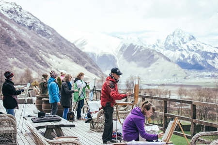 STEPANTSMINDA, GEORGIA - APRIL 19, 2015: Group of painters draw Kazbegi (Kazbek) mountain on the terrace at Stepantsminda village, Georgia.のeditorial素材