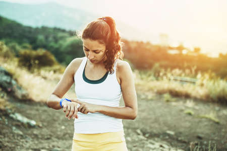 Woman using activity tracker. Outdoor fitness concept. Toned imageの写真素材