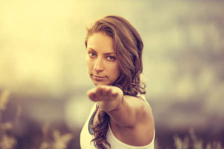Young woman standing in yoga pose with straight hands. Freedom and relax concept. Toned imageの写真素材