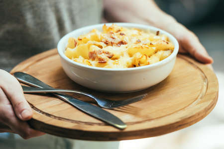 Plate of macaroni with cheese and bacon in hands. Toned pictureの写真素材