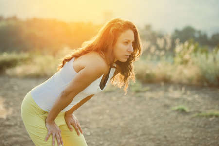 Young woman standing and resting after run. Wellness and sport concept. Toned imageの写真素材