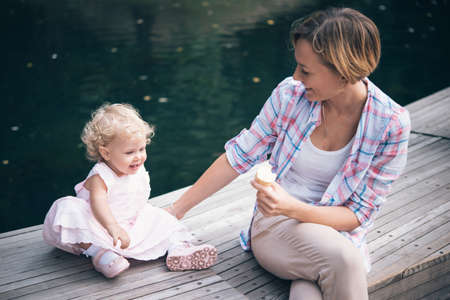 Mother and daughter eat ice-cream during a walk outdoors. Toned imageの写真素材