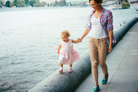 Young beautiful mother walks with her daughter near the riverの写真素材