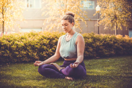 Yoga meditation in lotus pose in park.  Young woman in peace, soul and mind zen balance concept. Toned pictureの写真素材