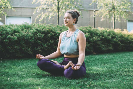 Yoga meditation in lotus pose in park.  Young woman in peace, soul and mind zen balance concept. Toned pictureの写真素材