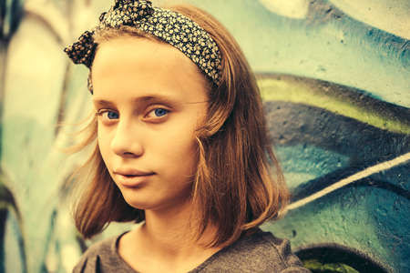 A portrait of a teenage girl with urban graffiti wall in the background. Toned imageの写真素材