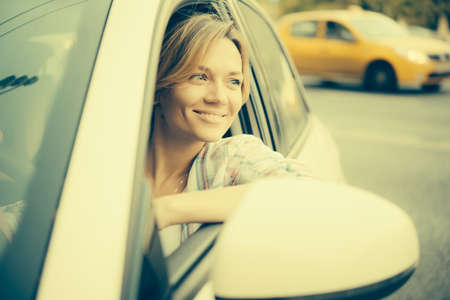 Young beautiful blonde woman drives a car. Toned image