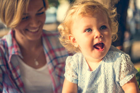 Beautiful blonde toddler girl with her mother. Toned imageの写真素材