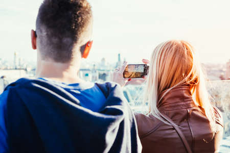 Young woman takes photo of Moscow city centre panorama with her mobile phone. Toned picture