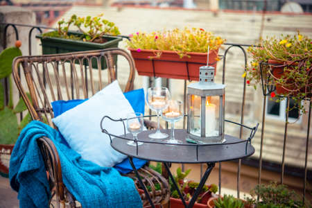 Beautiful terrace or balcony with cozy rattan armchair and candles on small iron tableの写真素材