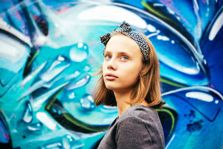 A portrait of a sad teenage girl with urban graffiti wall in the backgroundの写真素材