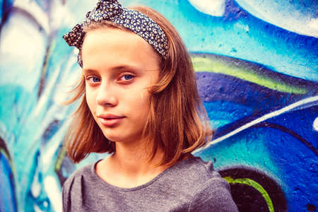 A portrait of a teenage girl with urban graffiti wall in the background. Toned imageの写真素材