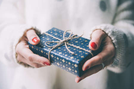 Woman's hands hold christmas or new year decorated gift box. Toned pictureの写真素材