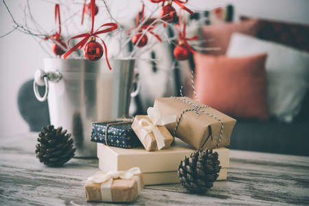 Christmas or new year decoration on modern wooden coffee table. Cozy sofa with pillows on a background. Living room interior and holiday home decor concept. Toned picture