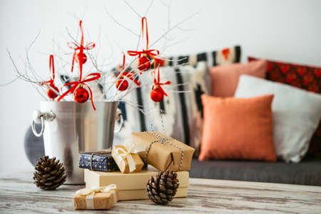 Christmas or new year decoration on modern wooden coffee table. Cozy sofa with pillows on a background. Living room interior and holiday home decor conceptの写真素材