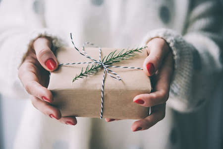 Woman's hands hold christmas or new year decorated gift box. Toned picture