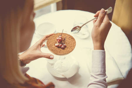 Woman eating italian dessert Tiramisu in cafe. Toned image