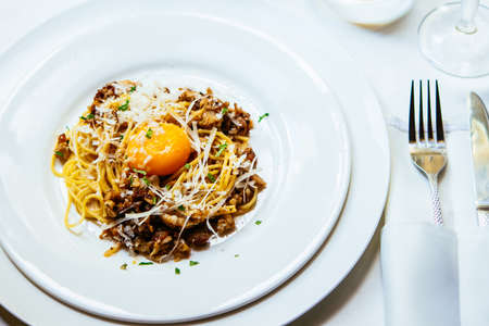 Pasta Carbonara with ham on white plate with parmesan and egg yolkの写真素材